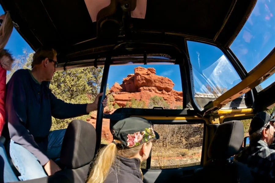 Tourists enjoying red canyon formations from inside a jeep