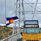 tourist waving from jeep while driving over Royal Gorge bridge and Colorado Flag